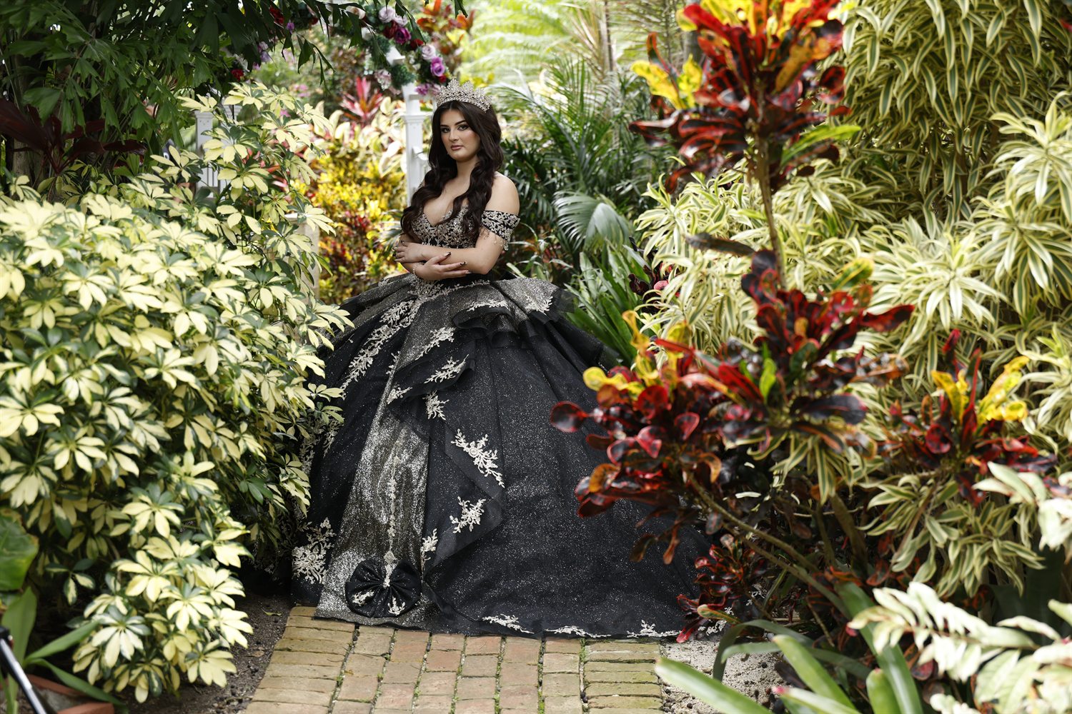 Isabella in her ballgown on a brick path among tropical foliage
