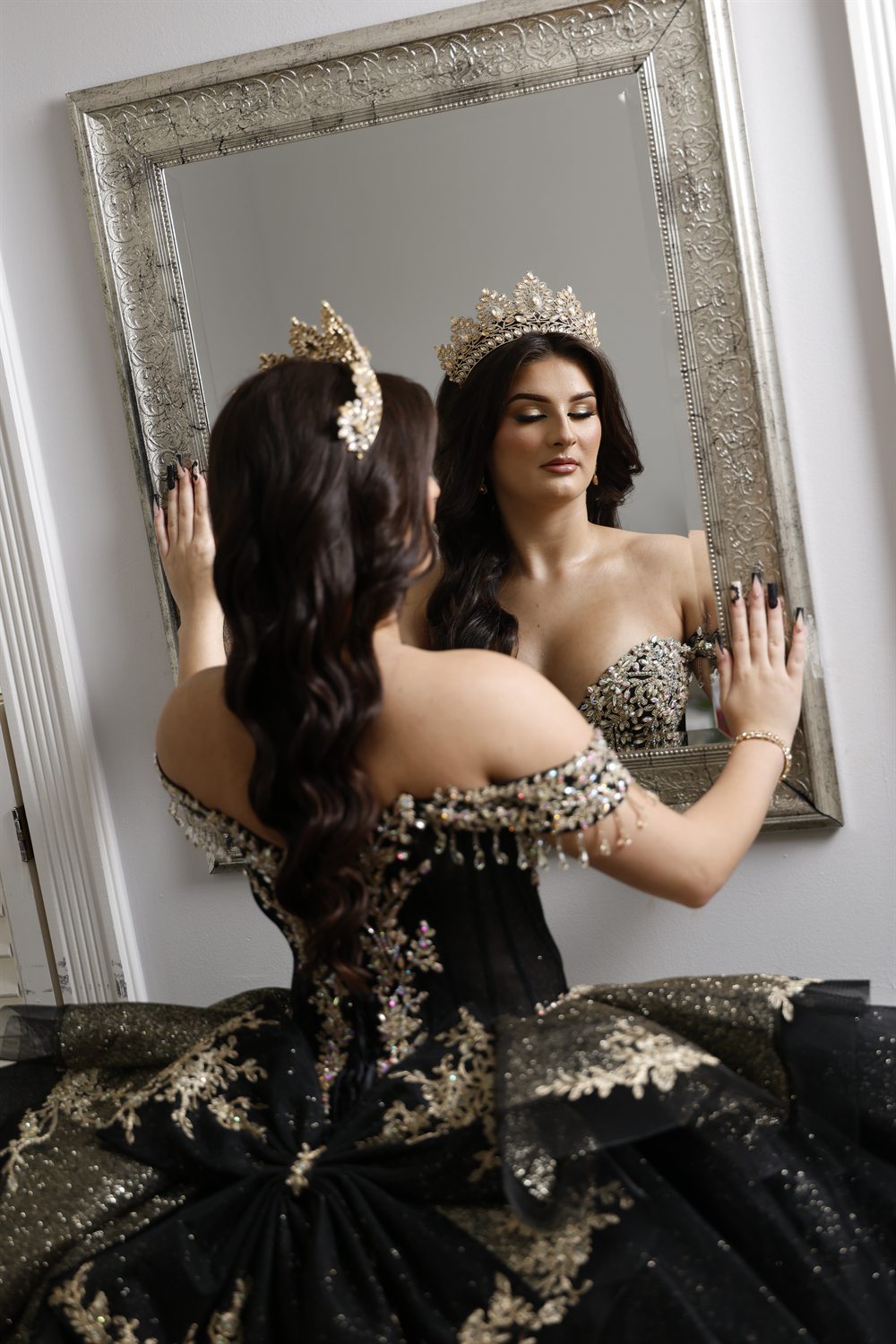 Isabella seated before the gilded mirror, gown fanned across the floor