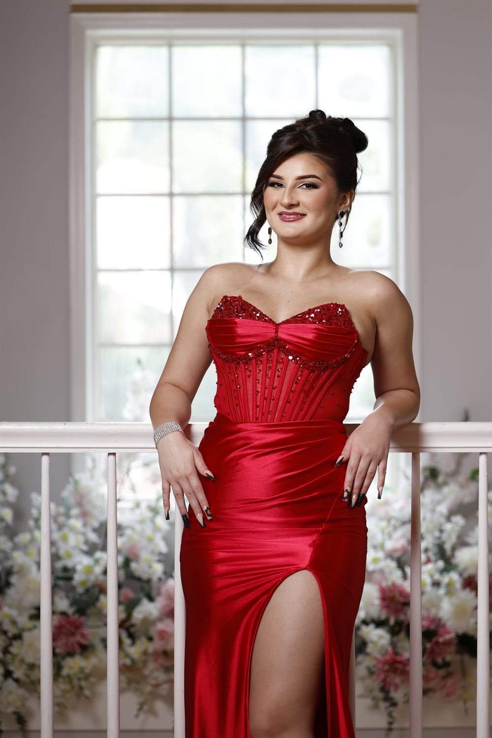 Isabella in a red satin gown by an arched window